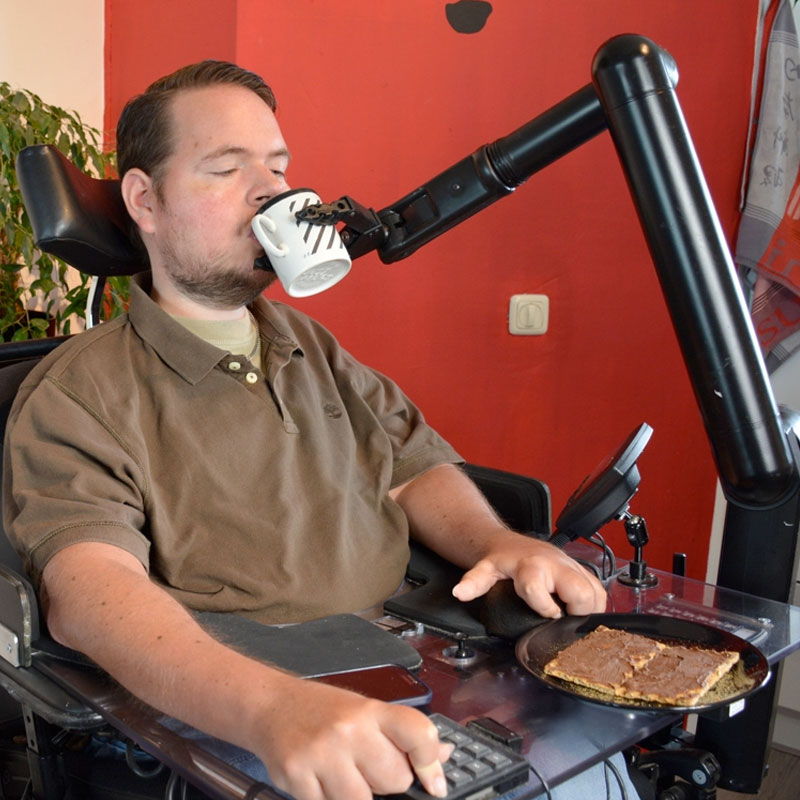 Roboterarm füttert Mann im Rollstuhl